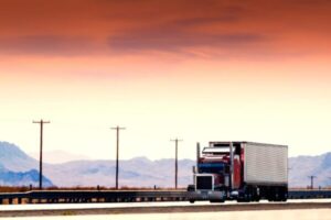 夕焼けの荒野を走る大型トラック