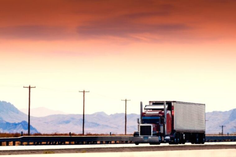 夕焼けの荒野を走る大型トラック