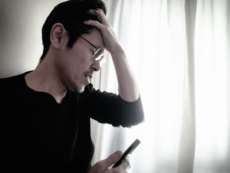 スマホを見て悩む男性
