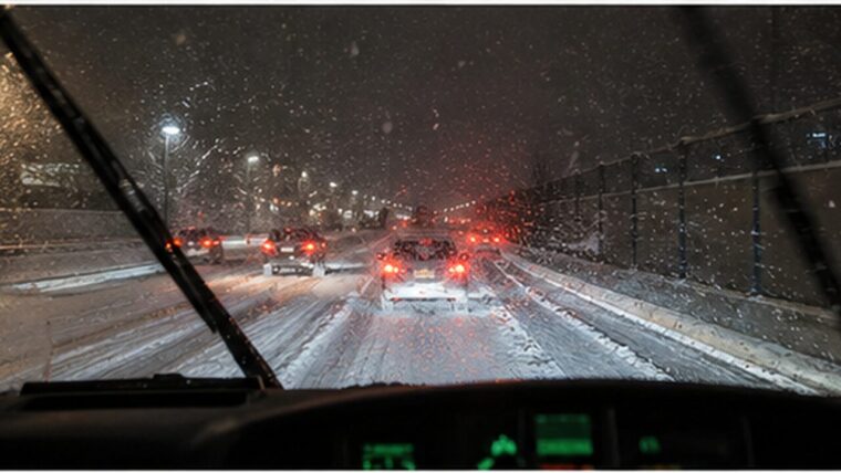 雪が降りしきる夜の高速道路、フロントガラス越しのテールランプ