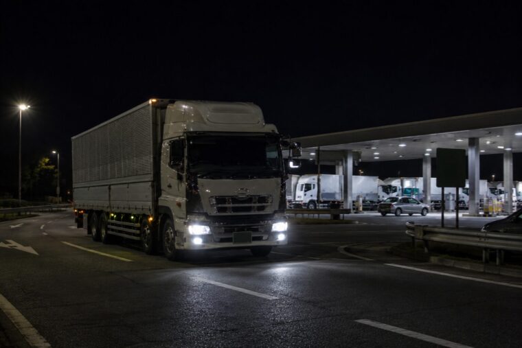 夜のSAから出発する大型トラック